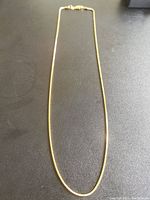 Full view of bicycle link chain necklace laid flat on black surface