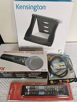 Photo showing Kensington Easy Riser laptop stand box, OFX Professional Microphone box, DP to DP 4K Ultra HD cable in packaging, and OFX universal remote control in packaging