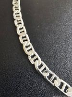 Close-up of silver-tone chain links showing interlocking rectangular pattern and polished surface.