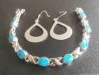 Top view of the bracelet showing blue oval stones set in sterling silver and paired teardrop-shaped sterling silver earrings.