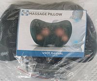 Sealy massage pillow still sealed in original plastic packaging along with user manual visible in packaging.