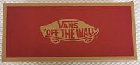 Top view of Vans shoe box lid with Vans 'Off The Wall' logo in red and tan.