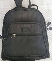 Front view of the mini strap-on knapsack showing its shape, front zippered pocket with leather pull, and Roots Canada logo patch.