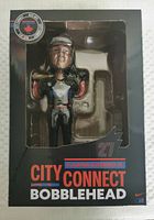 Front view of the bobblehead in black packaging with clear window showing figure, labeled City Connect Bobblehead with player name and number 27.