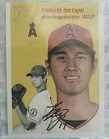 Front of Shohei Ohtani baseball card with facsimile signature in protective sleeve; sleeve shows some dirt but card itself appears intact.