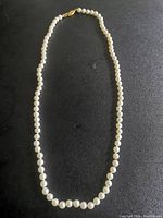 Full view of the white cream pearl necklace arranged in a circle showing the uniform pearls and length.