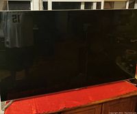 Front view of TV displaying off screen with reflection and red cloth beneath