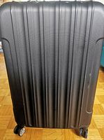 Front view of the full size black hard shell suitcase, showing textured ribbed design and 4 spinner wheels.