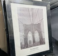 Front view of one black picture frame with bridge image placeholder and shrink-wrap.