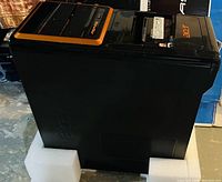 Side and front view of black Acer Aspire desktop tower with orange trim, resting on foam padding.