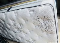Close-up of the white quilted mattress top showing Beautyrest logo and decorative stitching.