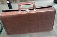 Brown textured leather or leather-like hard cassette carrying case with handle and metal latch.