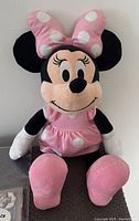 Front view of Disney Minnie Mouse plush showing pink polka dot bow, dress, and embroidered face detail.