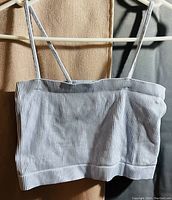 Grey crop top hanging on a hanger showing front and texture detail
