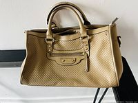 Front and side view of beige purse with woven pattern and double handles