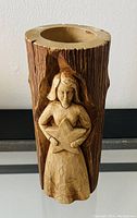 Wooden tealight candle holder carved with an angel holding a star, designed as a log segment with natural bark texture, hollowed for candle placement.