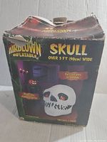 Box for Airblown Inflatable Halloween Skull. Box shows product image and description, specifies size over 3 feet wide and self-inflates in seconds. Box shows signs of wear.