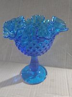 Side view of colonial blue hobnail glass compote showing ruffled edge and pedestal base