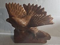 Front view of the hand carved wooden eagle sculpture showing detailed feathers and outspread wings.