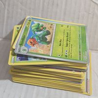 Stack of assorted Pokemon cards with visible top card Scovillain showing character image and stats.