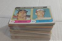Stack of vintage baseball cards showing the top card of 1973 Leading Firemen featuring John Miller and Mike Marshall.