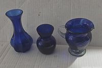 Three blue cobalt glass pieces: two vases and one small pitcher with handle, shown side by side for size comparison.