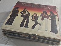 Stack of vintage vinyl records with the top album showing the band Journey on the cover.