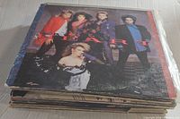 Stack of vintage vinyl records with Heart album on top showing the band members on the cover in colorful attire.