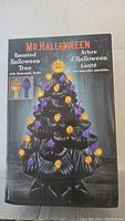 Photo of the box showing the product name 'Mr. Halloween Haunted Halloween Tree' with image of black ceramic tree decorated with orange and purple LED bulbs.
