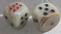Pair of alabaster dice showing front and partial sides, highlighting red and black inlays.