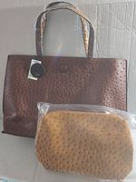 Brown textured tote handbag with ostrich leather pattern and brand tag visible on front