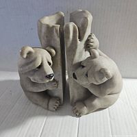 Pair of carved stone bear bookends facing each other showing the front details of the bear figures and central stone block.