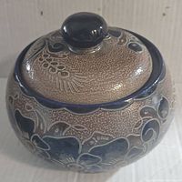 Side view of the salt glazed pottery bowl with lid showing floral and botanical designs in blue and beige.