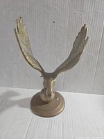 Front view of vintage brass eagle with detailed wings on orb base, against white background