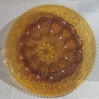 Top-down photo of vintage amber Indiana Glass Tiara egg dish showing detailed decorative patterns and scalloped edge.