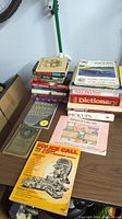 Photo of various books stacked on a table showing a variety of genres and titles.
