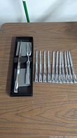 All items displayed on table: carving knife, meat fork, and ten small knives with silver-tone handles.