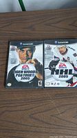 Photo showing two Nintendo GameCube game cases: Tiger Woods PGA Tour 2005 and NHL 2005 with EA Sports branding on front covers.