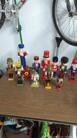 Full view of all eleven nutcrackers placed on a table beneath hanging bicycles