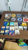 Photo of entire lot showing PC game CDs, software CDs, and multiple floppy disks arranged on a table.