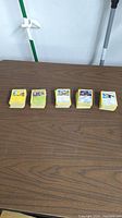 Five stacks of Pokemon cards arranged in a row on a table.
