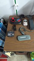 Photo of all vintage video game accessories on a table including joystick, printer, power switch, cable, and adapter.