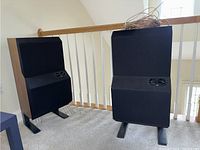 Two B&W DM6 speakers on stands with loose speaker wire coiled atop right speaker