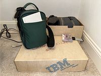 Photo showing boxes labeled 'camera film etc' and a carrying bag resting against the wall.