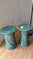 Two ceramic garden stools shown side by side with relief floral details, showcasing shape and finish.