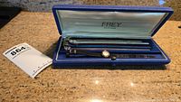 Frey presentation box opened on countertop showing watch attached to black strap and seven extra colored straps