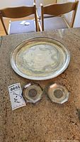 Overview of round tray and two hexagonal side dishes on countertop with lot tag