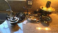 Overview of assorted serveware on countertop including teapots, trays, compote, metal bowls, and the large brass bowl