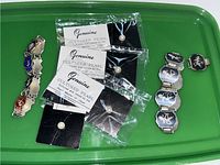 Two sterling silver stretch bracelets with enamel shield charms and four pairs of cultured pearl stud earrings in packaging, displayed on a green tray.