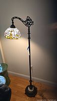 Full view of lamp showing arched stem, marble base and stained glass shade